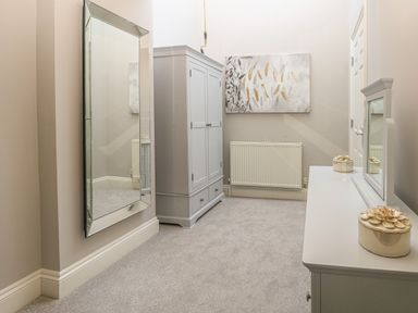 A hallway with a wall mirror a wardrobe a chest of drawers and a wall painting at Harbour Watch 2 in Weymouth