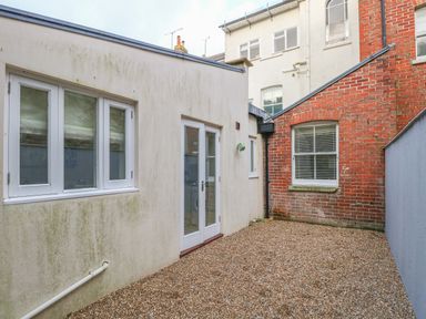 An outdoor area with gravel ground between white and red brick walls at Harbour Watch 2 in Weymouth