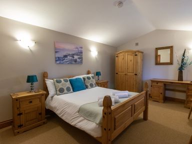 A bedroom with a wooden bed bedside tables wardrobe and desk at Riverhouse Lodge in Upwey
