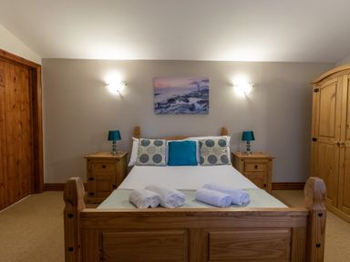 A bedroom with a wooden bed frame and side tables with lamps at Riverhouse Lodge in Upwey