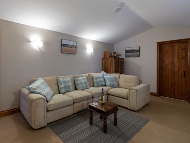 A living room with a beige sectional sofa and blue plaid cushions a wooden coffee table and a wooden cabinet at Riverhouse Lodge in Upwey