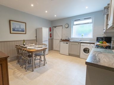 A kitchen with a dining table set for four near a refrigerator and appliances under a window at Riverhouse Lodge in Upwey