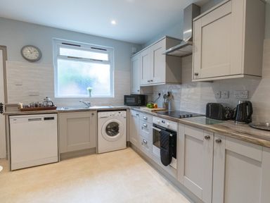 A kitchen with cabinets dishwasher washing machine oven and microwave at Riverhouse Lodge in Upwey