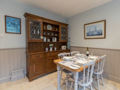 A dining area with a wooden table set for four and a wooden hutch with dishes at Riverhouse Lodge in Upwey