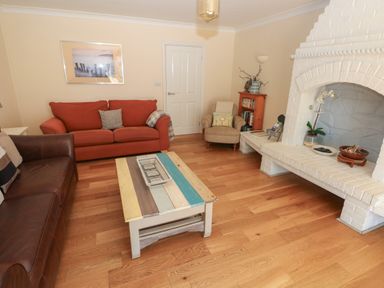 A living room with two sofas a multicolored wooden coffee table a white brick fireplace and a small bookcase at Yr Hen Ardd in Dale near Milford Haven