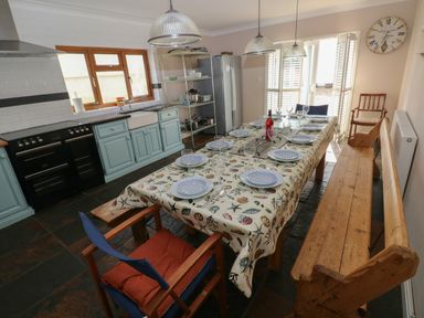 A kitchen with a dining table set for eight with a tablecloth and plates at Yr Hen Ardd in Dale near Milford Haven