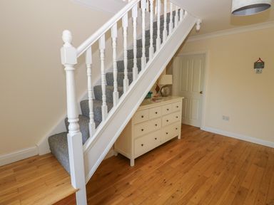 A staircase with gray carpet and white banister next to a white dresser with drawers in a hallway at Yr Hen Ardd in Dale near Milford Haven