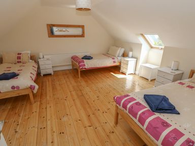 A bedroom with three single beds wooden floors and bedside tables at Yr Hen Ardd Dale near Milford Haven