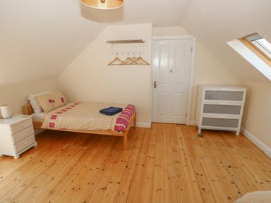A bedroom with a bed nightstand chest of drawers and a closed door at Yr Hen Ardd in Dale near Milford Haven