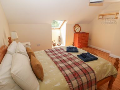 A bedroom with a double bed pillows and towels a wooden chest of drawers and a wall mounted clothes rack at Yr Hen Ardd in Dale near Milford Haven