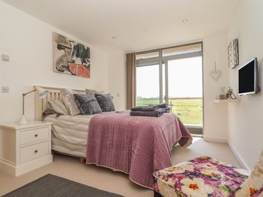 A bedroom with a double bed and bedside table next to a sliding glass door at 8 Cribbar in Newquay
