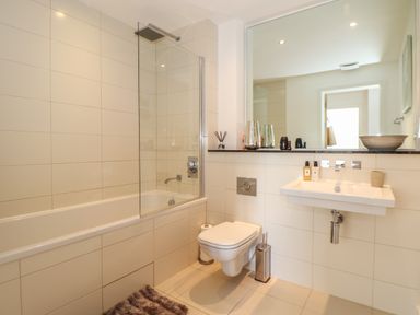 A bathroom with a bathtub shower combination toilet and sink with a large mirror at 8 Cribbar in Newquay