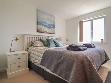 A bedroom with a double bed two bedside tables and a window at 8 Cribbar in Newquay