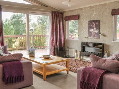 A living room with sofas and a wooden coffee table near sliding glass doors at Bulmer Farm Lodge in Malton