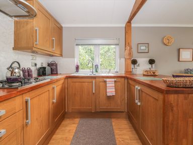 A kitchen with wooden cabinets a sink window and countertop appliances at Bulmer Farm Lodge in Malton