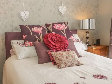 A bed with multiple decorative pillows and a lamp on a bedside table at Bulmer Farm Lodge in Malton