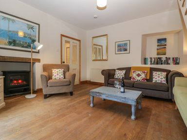 A living room with armchair fireplace couch coffee table and books at Woodlands Cottage in Docklow near Leominster