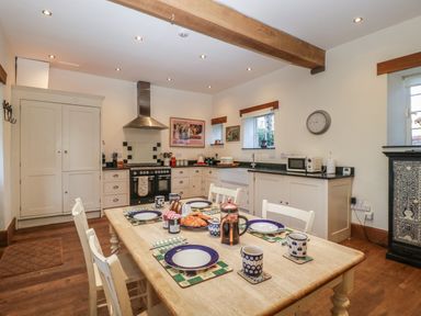 A kitchen with a dining table set with plates cups and croissants at Woodlands Cottage Docklow near Leominster