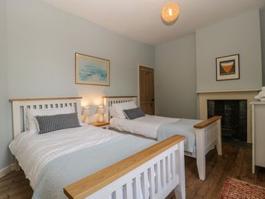 A bedroom with two single beds a wooden floor and a fireplace at Woodlands Cottage Docklow near Leominster
