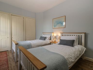 A bedroom with two single beds bedside table with lamps and a framed picture on the wall at Woodlands Cottage in Docklow near Leominster