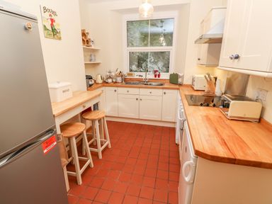 A kitchen with wooden countertops stools a refrigerator and a window at Elmbank in Looe