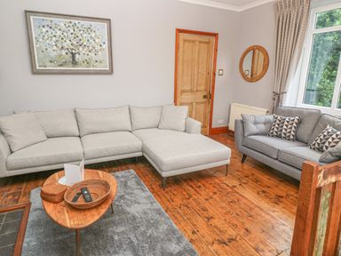 A living room with two sofas a wooden coffee table and a wall painting at Elmbank in Looe