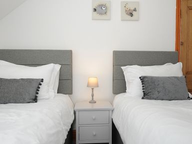A bedroom with two single beds a nightstand and a table lamp at Elmbank in Looe