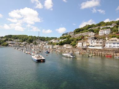 A harbor with boats moored in water and houses on a hillside at Elmbank in Looe