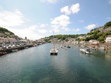 A harbor with boats moored along both sides and houses on hills at Elmbank in Looe
