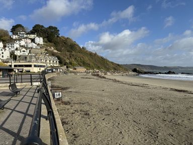 A beach with sand sea and houses on a hill at Elmbank in Looe