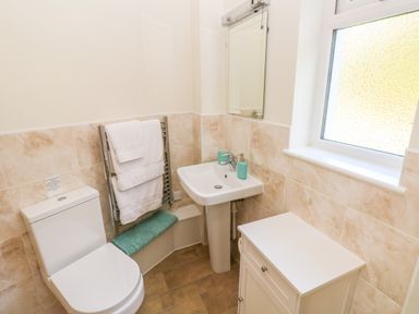 A bathroom with a toilet sink mirror towel rack and cabinet at Little Freestone in Carew