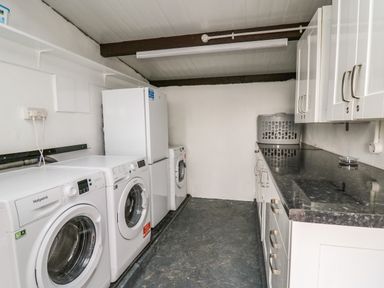 A laundry room with washing machines a fridge cabinets and a laundry basket at Gwynant in Pontrhydfendigaid