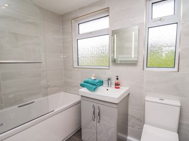 A bathroom with a bathtub a sink with towels a mirror and a toilet at Gwynant in Pontrhydfendigaid