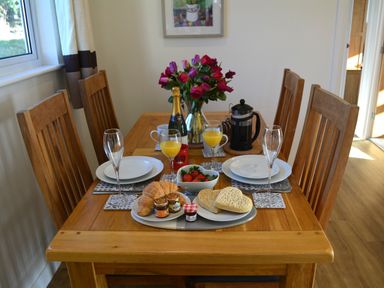 A dining table set with plates glasses orange juice strawberries croissants and heart shaped bread at Gwynant in Pontrhydfendigaid