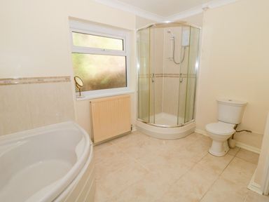 A bathroom with a bathtub shower enclosure toilet window and radiator at Glan Gors in Llanerchymedd