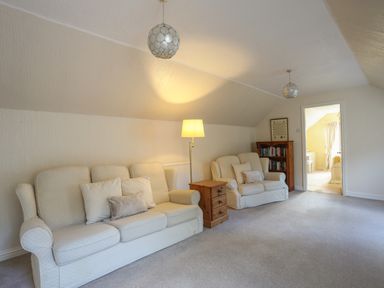 A living room with two sofas a wooden side table and a bookshelf at Glan Gors in Llanerchymedd