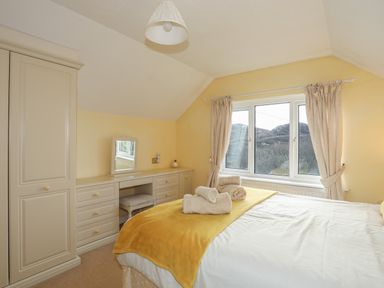 A bedroom with a bed with towels on it and a dressing table with a mirror and a window at Glan Gors in Llanerchymedd