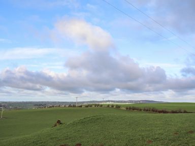 A rural landscape with green fields wind turbines and telephone poles at Glan Gors in Llanerchymedd