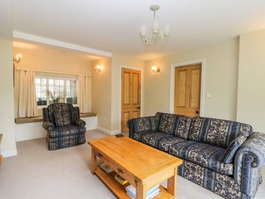 A living room with patterned sofa armchair wooden coffee table and window seat at Stakesby House Apartment 1 in Whitby