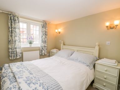 A bedroom with a double bed between two bedside tables under wall lights at Stakesby House Apartment 1 in Whitby