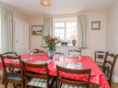 A dining room with a red polka dot tablecloth and flowers on the table at The Pink House in Rhosneigr