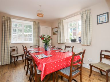 A dining room with a red polka dot tablecloth on a table set with glassware and placemats at The Pink House in Rhosneigr