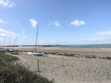 Boats on a sandy beach near the sea with a few clouds in the sky at The Pink House in Rhosneigr