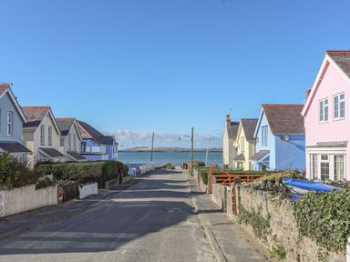 A street with colorful houses leading to a body of water at The Pink House in Rhosneigr