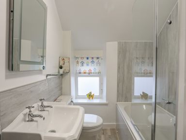A bathroom with a sink toilet bathtub and window with patterned blind at The Pink House in Rhosneigr