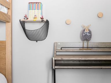 A wall with a small shelf holding books and figurines a wooden desk with a decorative reindeer and two wooden wall hooks at Beach Haven in West Bexington