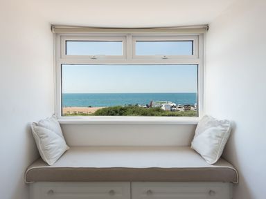 A window seat with cushions overlooking the beach and ocean at Beach Haven in West Bexington
