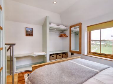 A bedroom with a bed a window a closet with hangers and baskets and a mirror at The Folly in Weobley