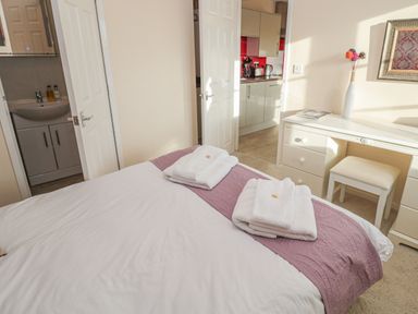 A bedroom with a bed towel arrangement a vanity table and an open door leading to a bathroom and kitchen at Vallum Kiosk in Haltwhistle