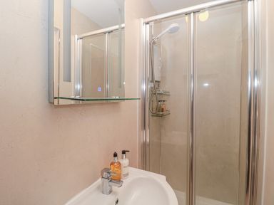 A bathroom with a sink a mirror cabinet a shower enclosure with glass doors and showerhead at Vallum Kiosk in Haltwhistle
